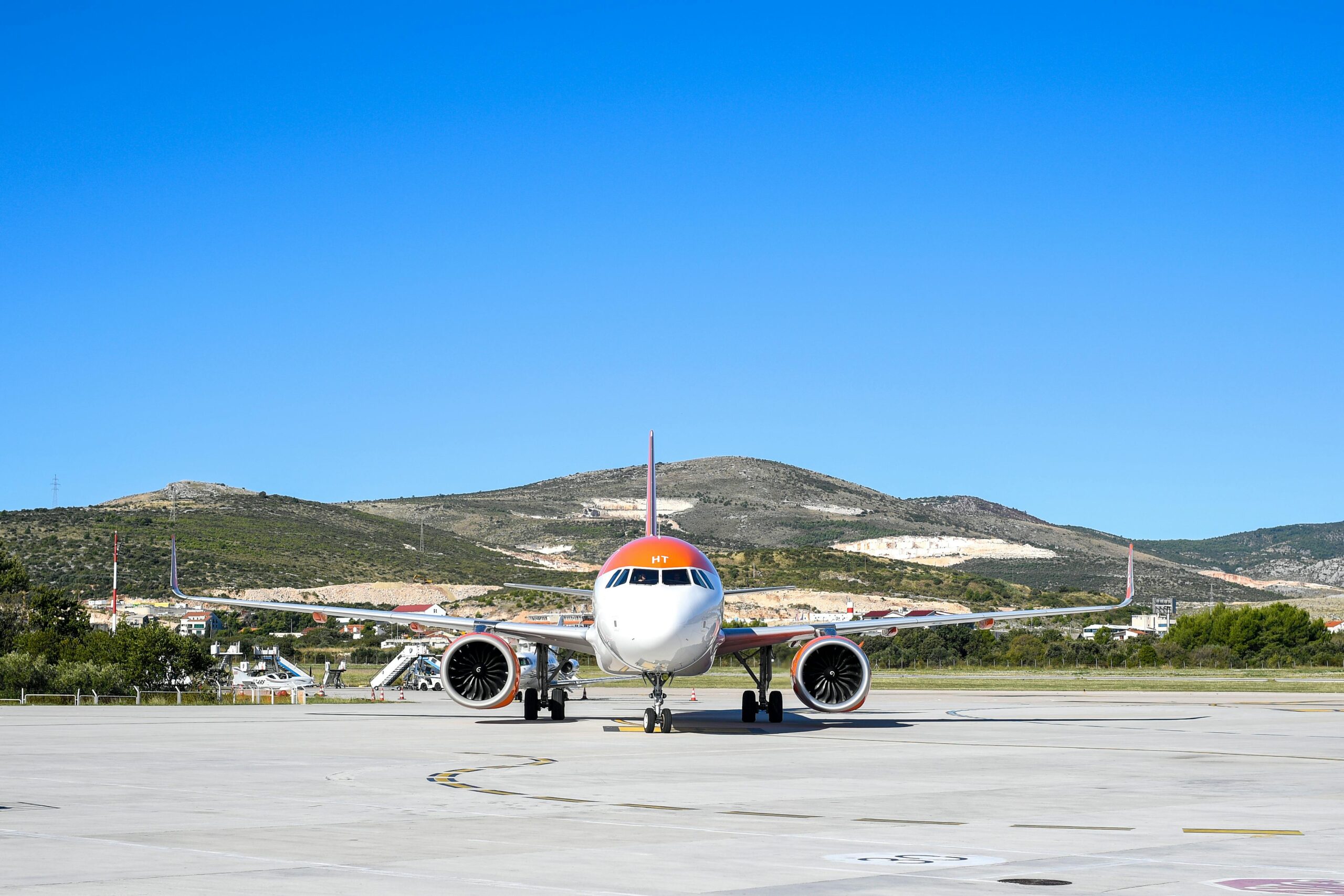 Airbus A320 aircraft parked at Split Airport in Croatia with scenic mountain backdrop.